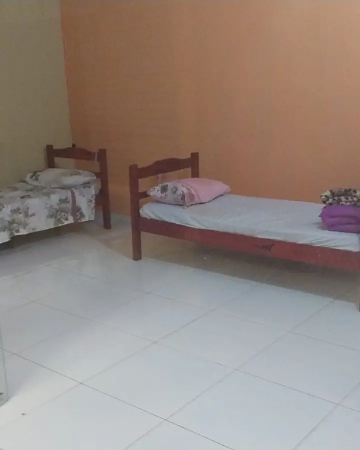 Quarto duplo com duas camas de madeira e piso claro