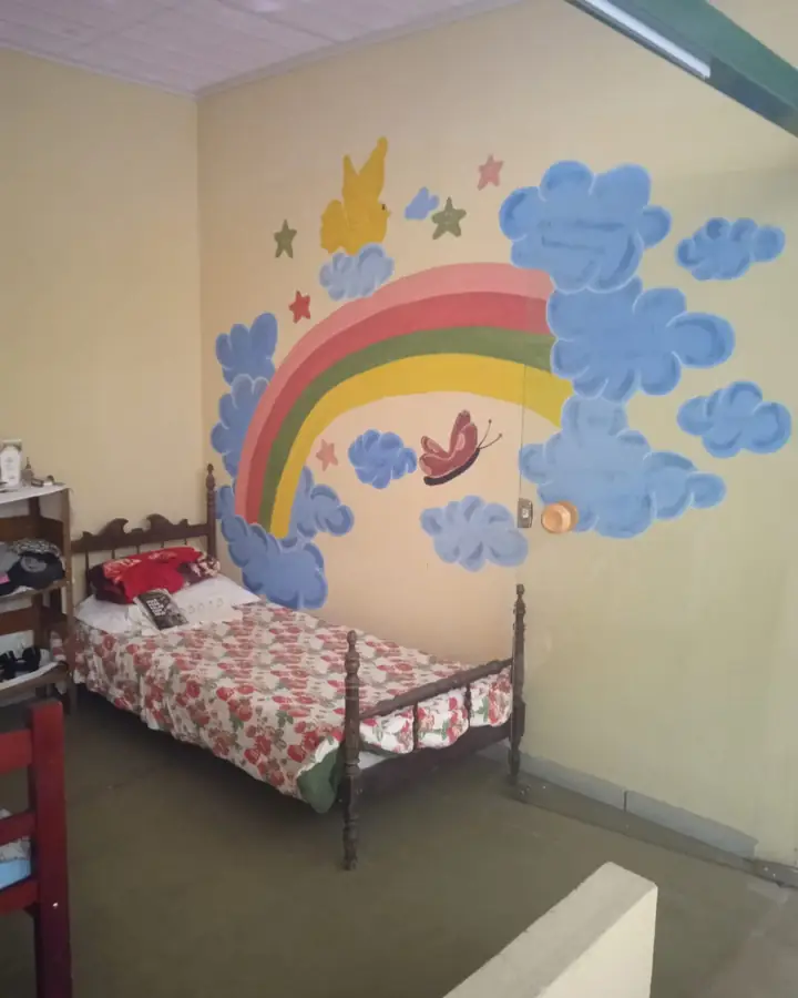 Quarto com cama de madeira e mural de arco-íris pintado na parede